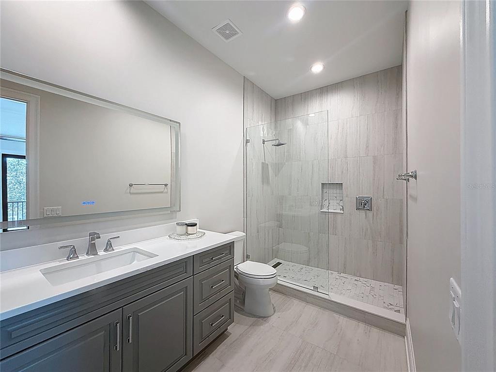 7394 Gathering Court Reunion, FL 34747 - Photo 29 of 44 a bathroom with a double vanity sink toilet mirror and shower