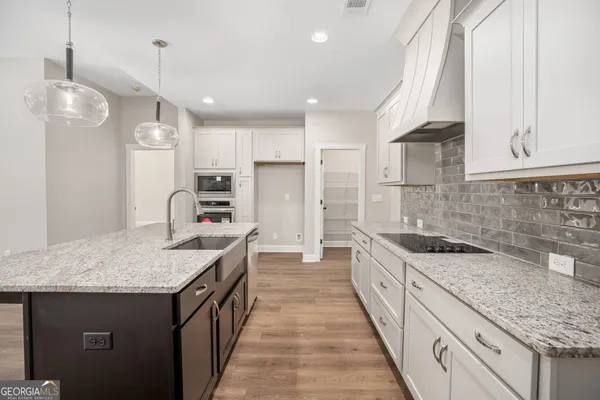 a kitchen with granite countertop kitchen island stainless steel appliances a sink stove and cabinets