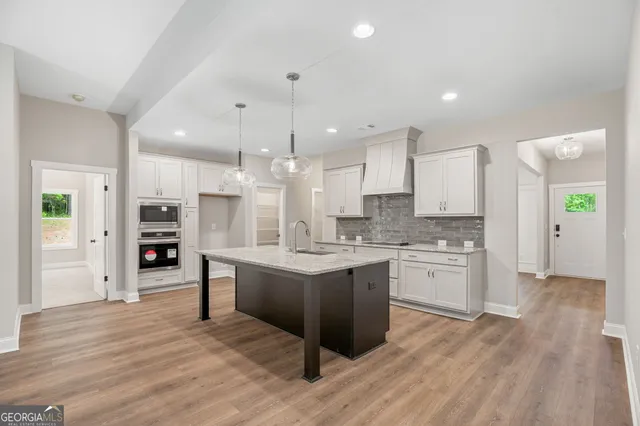 a large kitchen with stainless steel appliances granite countertop a large center island a stove a refrigerator and a sink