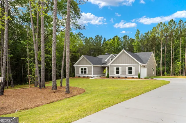 a white house with a big yard and large trees