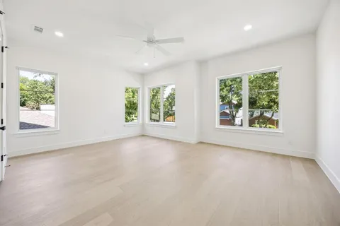 a view of an empty room with a window and a kitchen