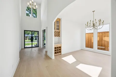a view of an empty room with chandelier and wooden floor