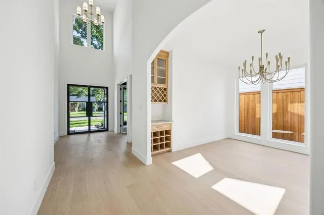 a view of an empty room with chandelier and wooden floor