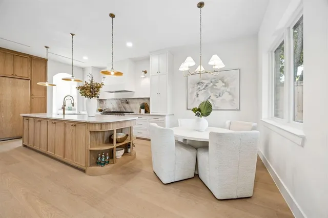 a kitchen with kitchen island granite countertop a stove a sink a refrigerator and a dining table with wooden floor