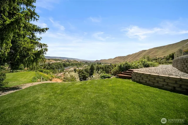 a view of a green field with mountains in the background