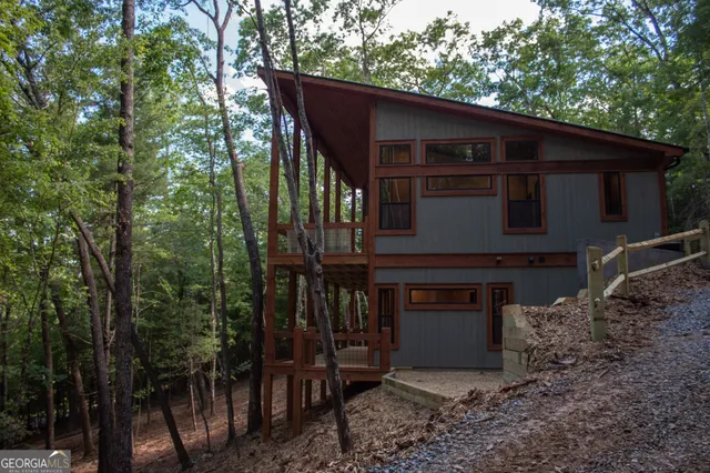 a view of a house with a yard plants and large tree
