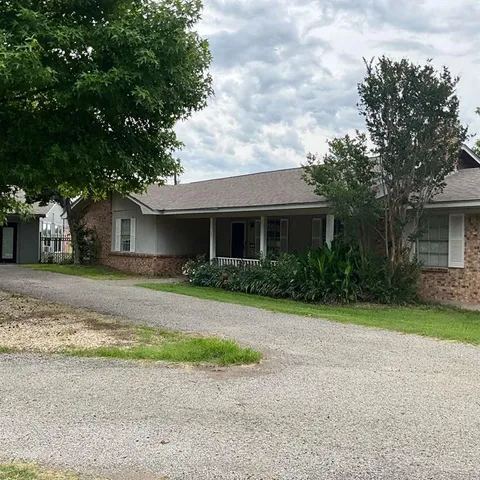 a front view of a house with a garden and trees