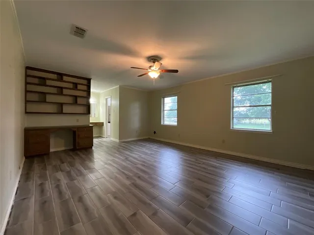 an empty room with wooden floor chandelier fan and windows