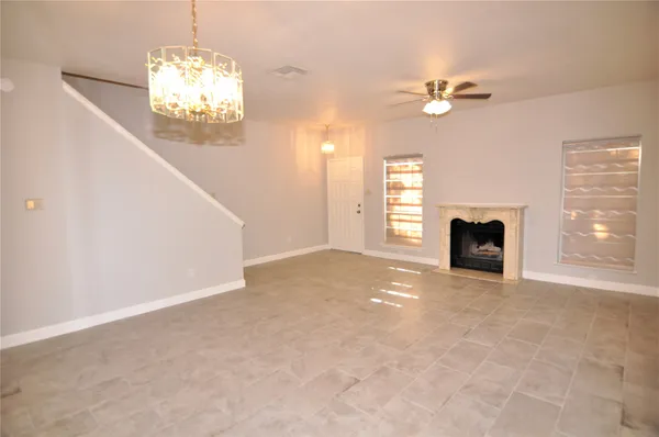 a view of a livingroom with a fireplace a chandelier and windows