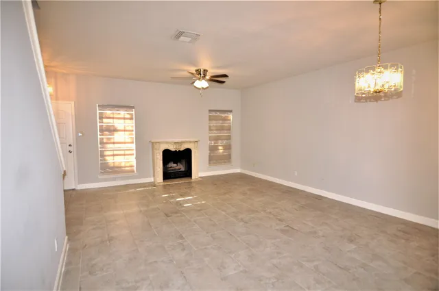 an empty room with windows and fireplace