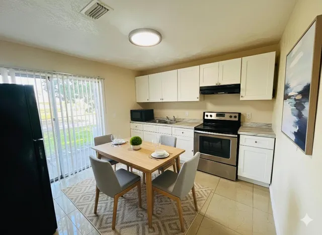 a kitchen with a stove a sink a microwave a refrigerator and cabinets
