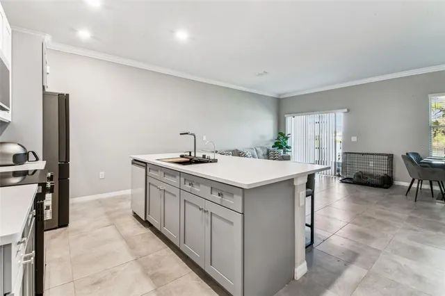 a kitchen with stainless steel appliances kitchen island granite countertop a dining table chairs and a living room