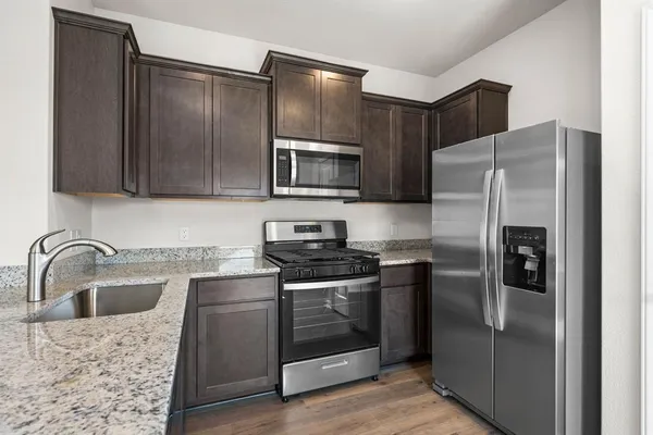 a kitchen with stainless steel appliances granite countertop a refrigerator a stove a sink and a microwave