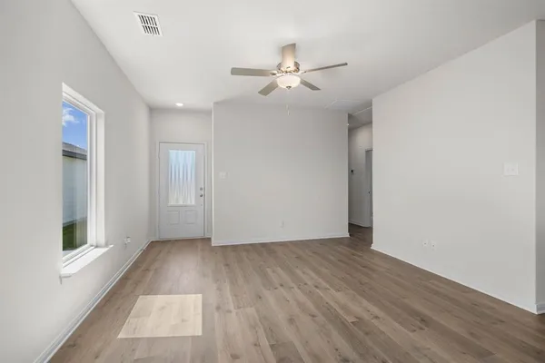 a view of an empty room with wooden floor and a window