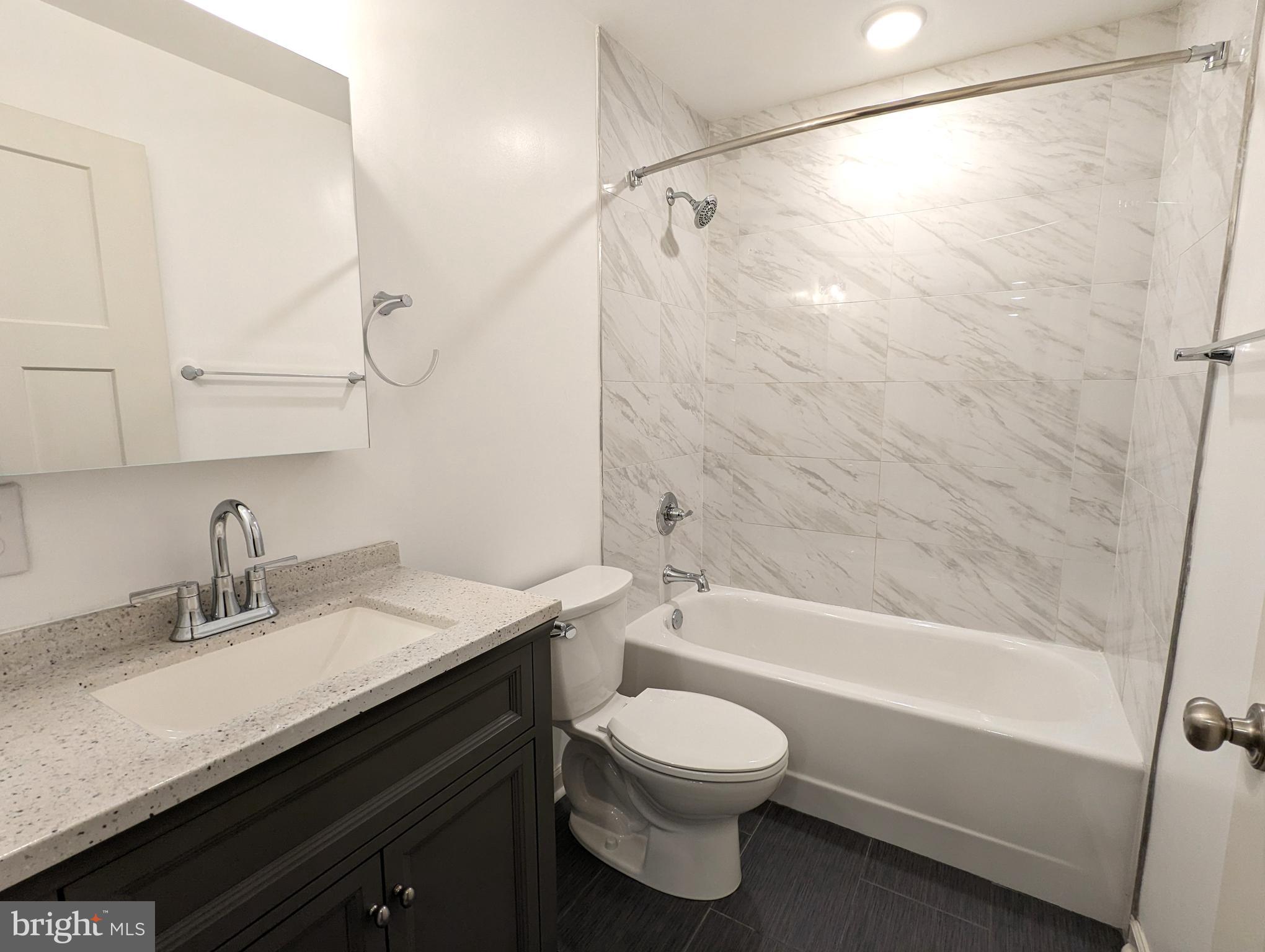 5420 Ridge Avenue, Unit 104 Philadelphia, PA 19128 - Photo 6 of 7 a bathroom with a sink a toilet and a bathtub