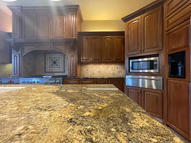 a kitchen with granite countertop wooden cabinets and stainless steel appliances
