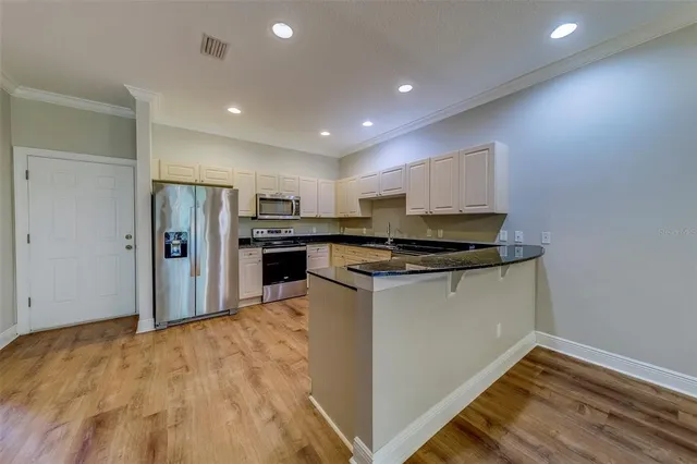 a kitchen with granite countertop white cabinets and stainless steel appliances