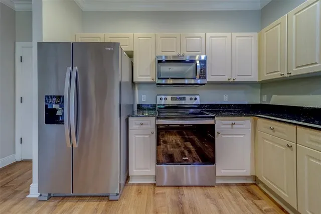 a kitchen with granite countertop white cabinets and stainless steel appliances