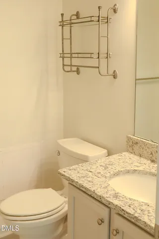 a bathroom with a granite countertop sink and a toilet