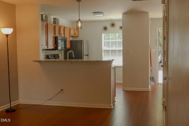 a view of a kitchen with refrigerator and wooden floor