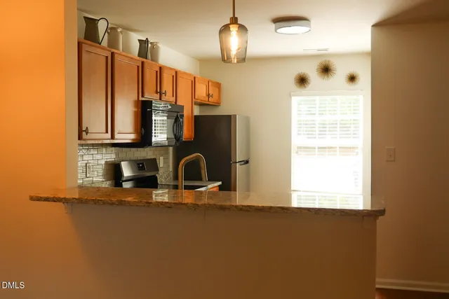 a kitchen with stainless steel appliances kitchen island granite countertop a stove a sink and a microwave