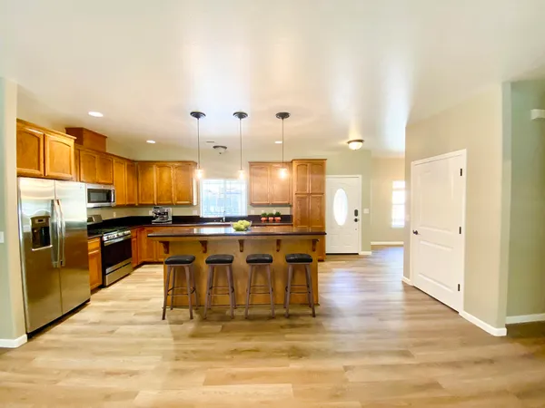 a view of a kitchen with kitchen island stainless steel appliances refrigerator stove top oven and cabinets