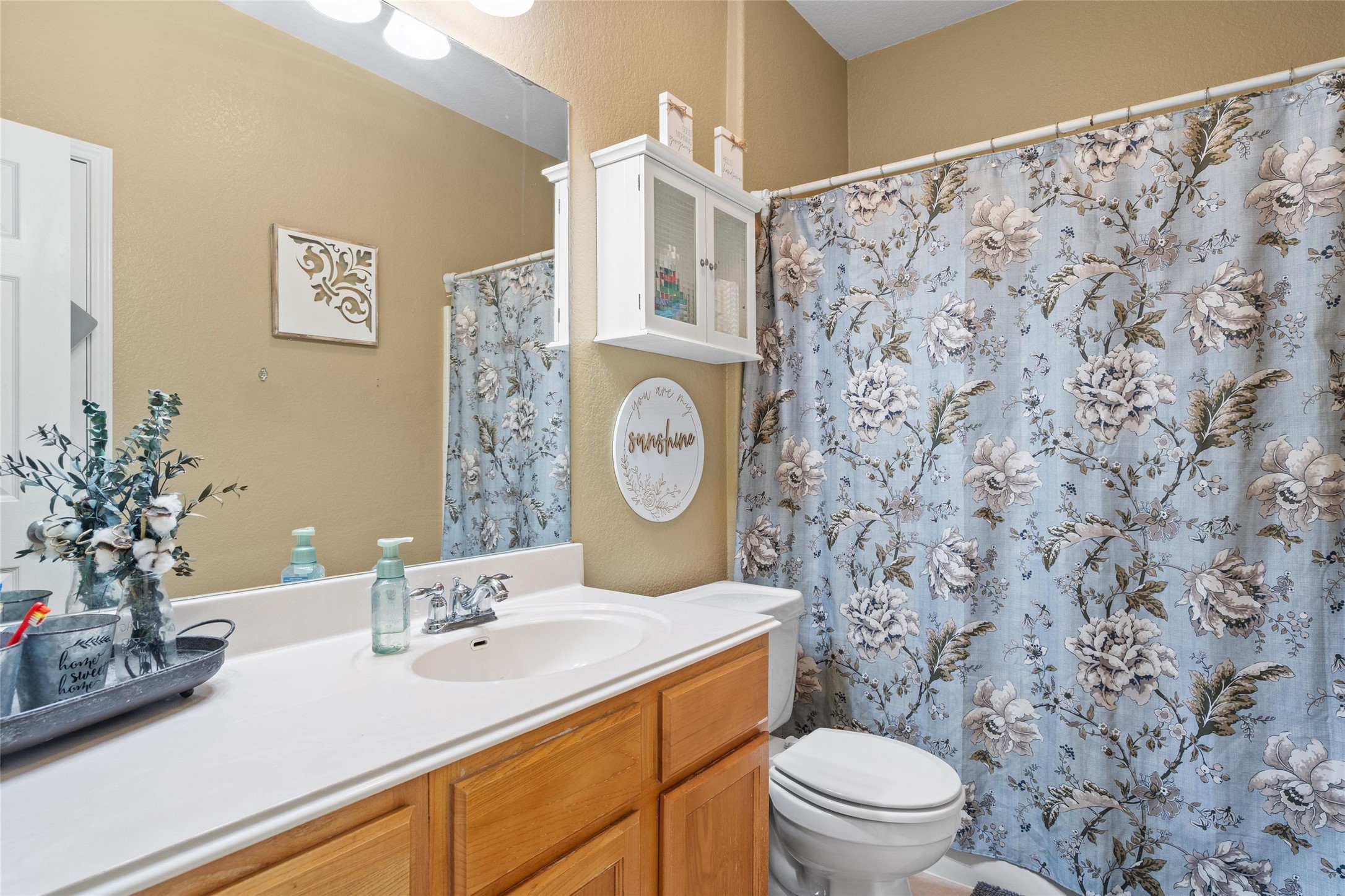 149 Dropper Kyle, TX 78640 - Photo 28 of 33 Warm wood cabinetry and an integrated solid surface sink anchor this functional bathroom layout.