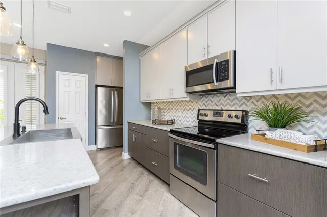 a kitchen with kitchen island wooden floors appliances and cabinets