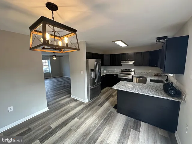 a kitchen with stainless steel appliances a stove a refrigerator a sink and dishwasher with wooden floor