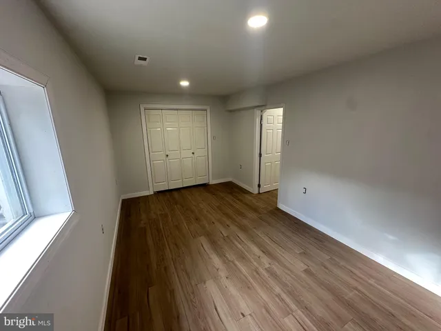 a view of empty room with wooden floor and fan
