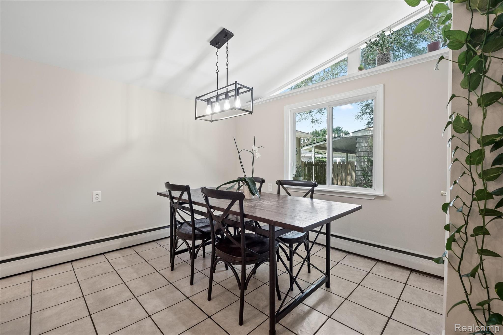 870 Pine Tree Road Lake Orion, MI 48362 - Photo 13 of 32 Dining area featuring vaulted ceilings, a contemporary rectangular light fixture, neutral wall tones, and tile flooring