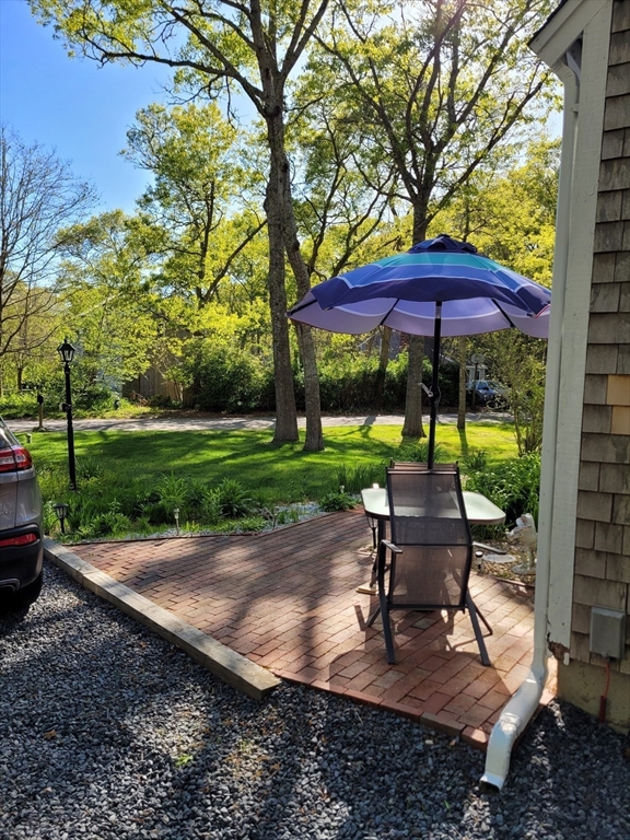92 Santuit Pond Road Mashpee, MA 02649 - Photo 21 of 23 a view of a table and chairs in backyard under a large tree