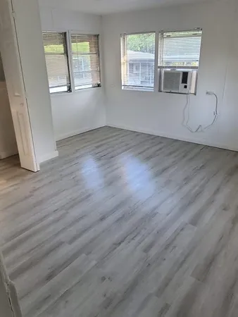 a view of an empty room with wooden floor and windows