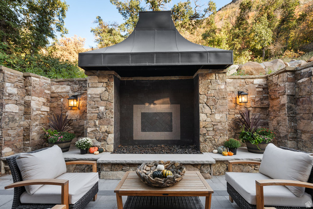1141 South Oak Leaf Lane Springville, UT 84663 - Photo 123 of 147 Outdoor stone fireplace with a fluted metal hood, flanked by stone walls and integrated lighting fixtures