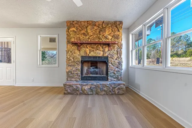 a view of an empty room with wooden floor fireplace and a window