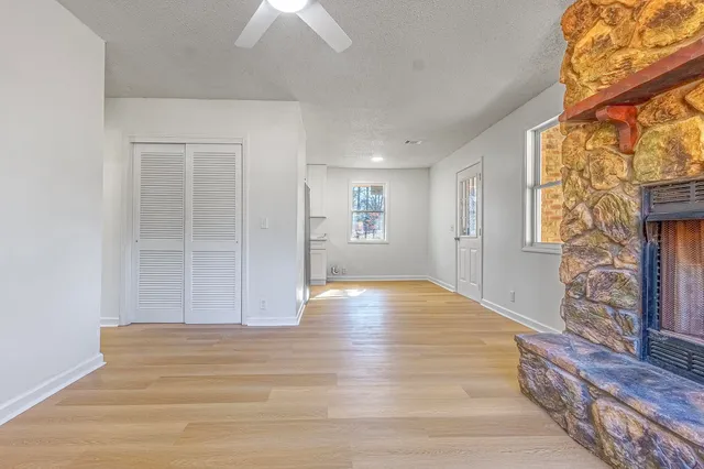 a view of an empty room with wooden floor and a window