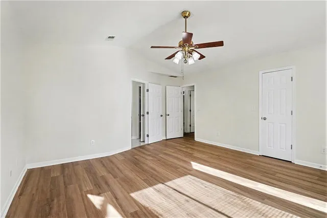a view of empty room with wooden floor and ceiling fan