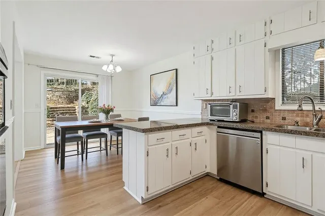 a kitchen with granite countertop a stove a sink and white cabinets with wooden floor