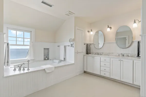 a spacious bathroom with a double vanity sink mirror and bathtub