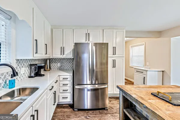 a kitchen with stainless steel appliances granite countertop a refrigerator a sink a stove and white cabinets
