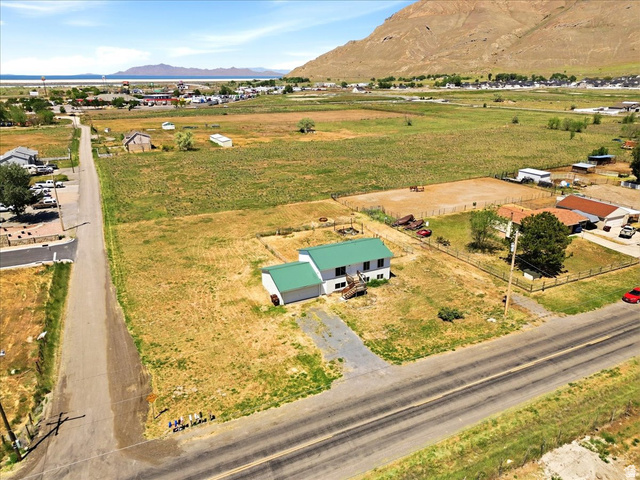 1613 Sunset Road Lake Point, UT 84074 - Photo 32 of 33 Expansive property featuring a residence with a green roof, surrounding agricultural fields, and a distant body of water with mountains
