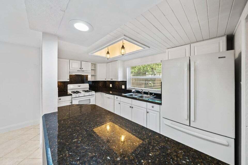 5889 Williamson Road Jupiter, FL 33458 - Photo 14 of 27 a kitchen with stainless steel appliances kitchen island granite countertop a refrigerator and a stove top oven