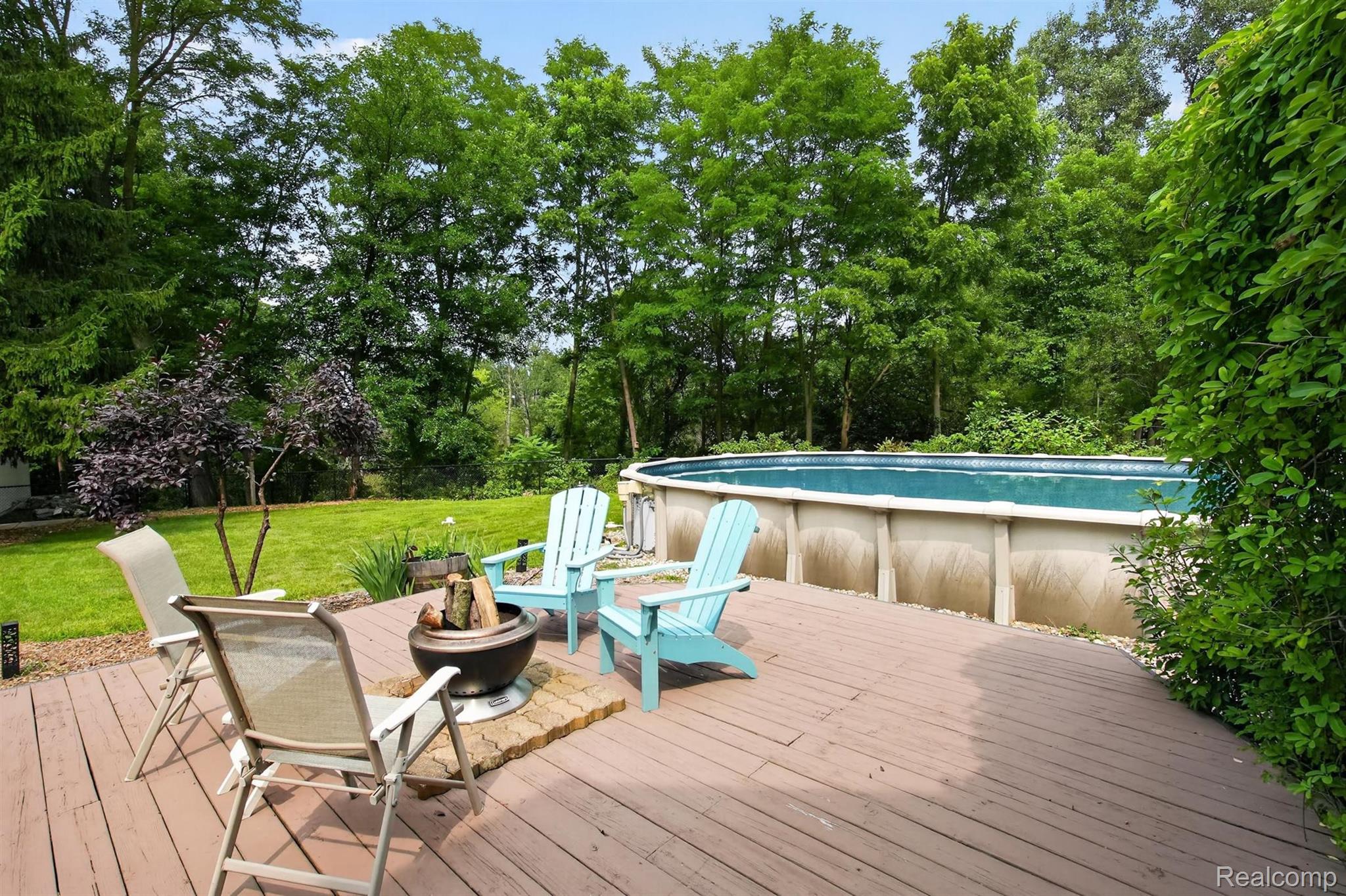 9319 Faussett Road Fenton, MI 48430 - Photo 53 of 70 Expansive outdoor decking featuring a fire pit, mature trees, and a swimming pool