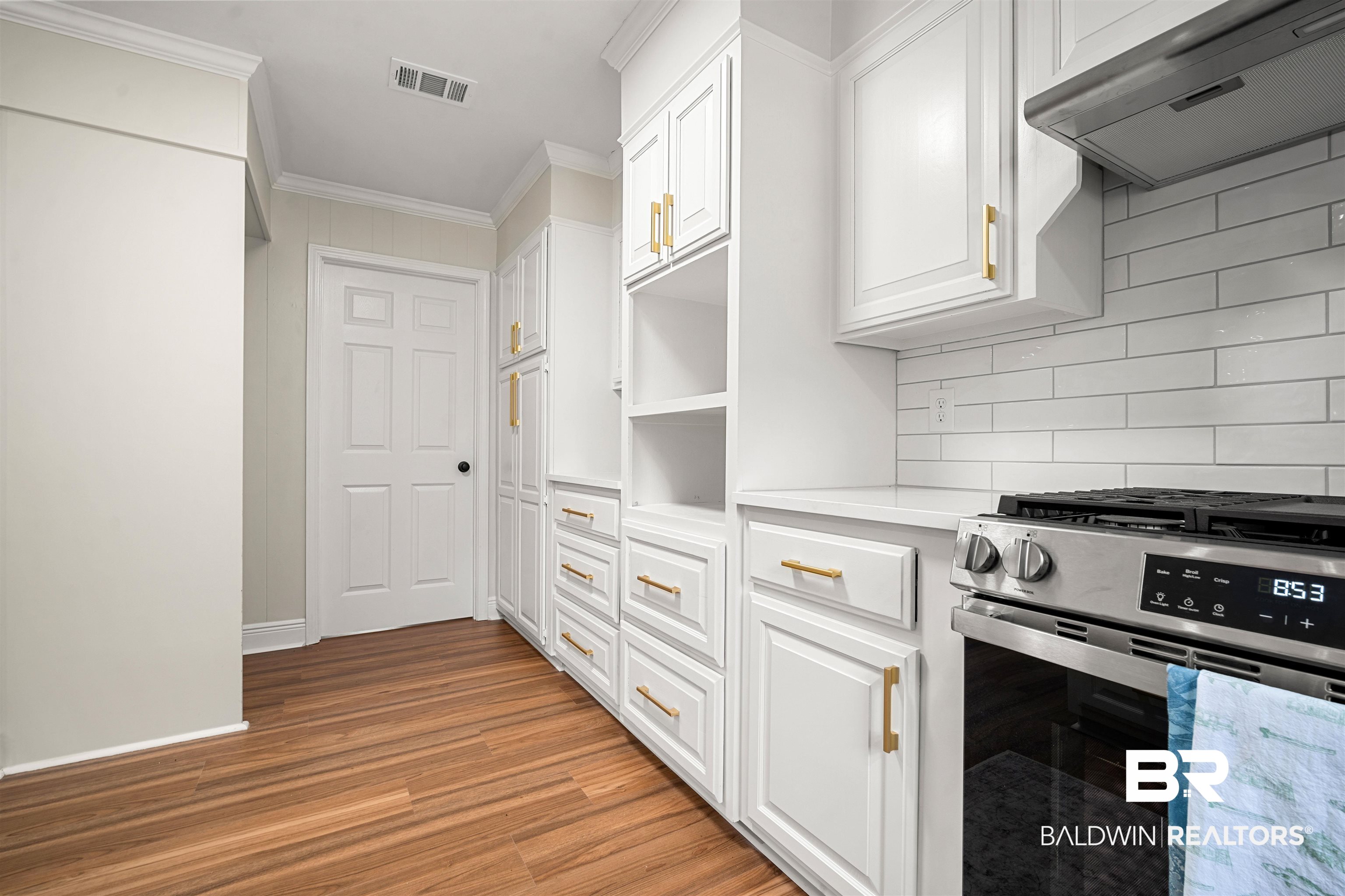 3050 Lacoste Road Mobile, AL 36618 - Photo 12 of 30 Kitchen featuring stainless steel gas range oven, ventilation hood, white cabinetry, crown molding, and backsplash
