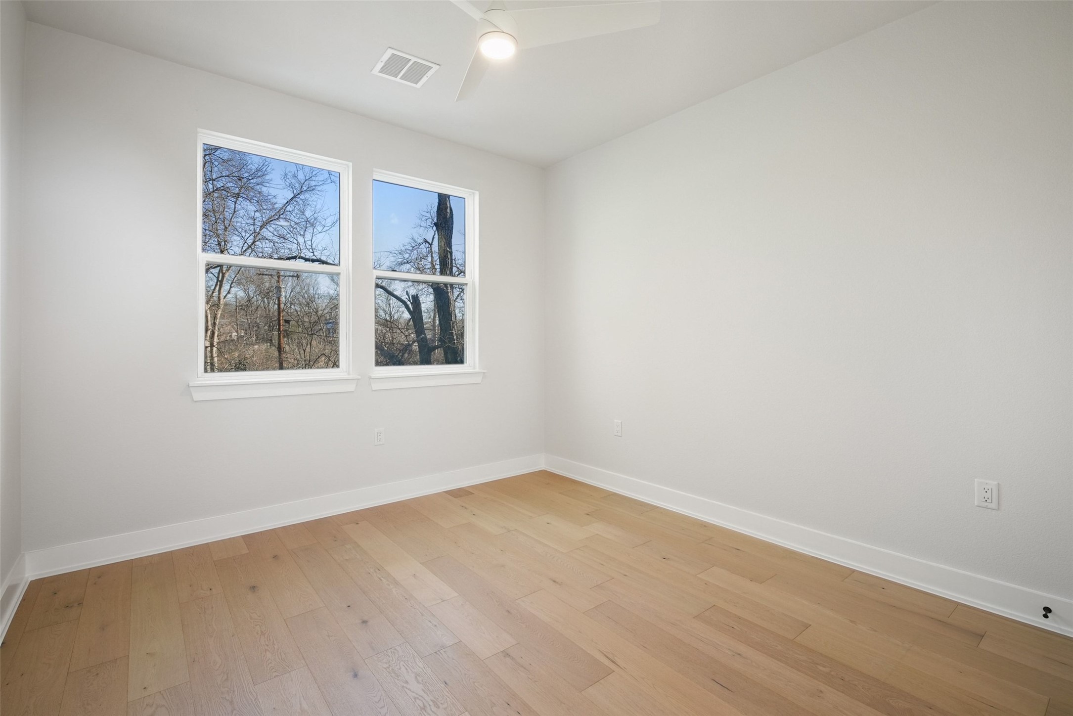 5109 Stone Gate Drive, Unit 2 Austin, TX 78721 - Photo 20 of 36 Neutral-toned room with wood-finish flooring, white baseboards, and two double-hung windows