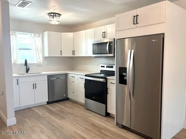 a kitchen with a refrigerator sink and cabinets