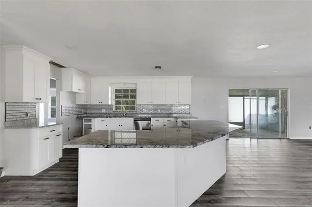a view of a kitchen with kitchen island a counter top space a sink stainless steel appliances and cabinets