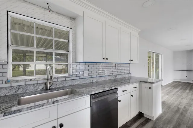 a kitchen with granite countertop a sink and a white cabinets