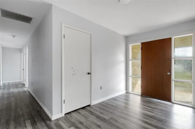 a view of an empty room with wooden floor and a window
