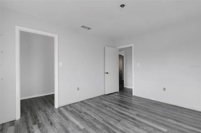 a view of an empty room with wooden floor and closet